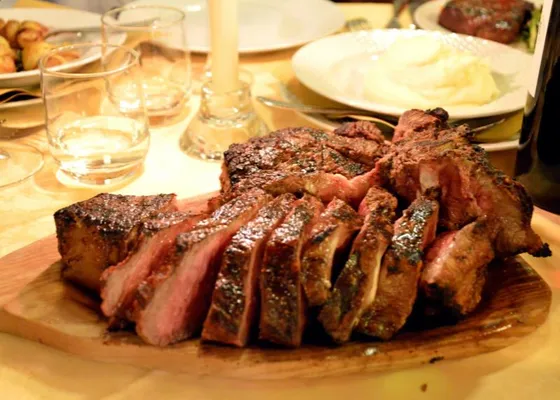 A thick grilled T-bone steak with a browned crust, served on a board