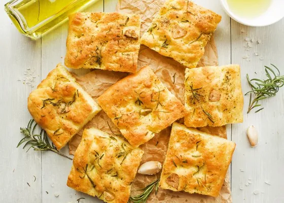 Squares of golden dimpled focaccia with rosemary on a board