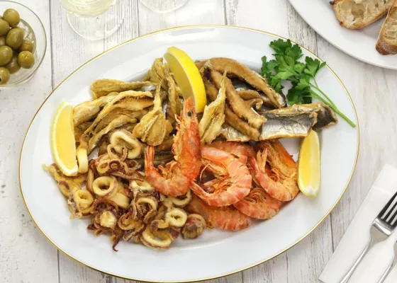 A platter of fried squid rings, shell-on shrimp and small fish with lemon wedges and parsley