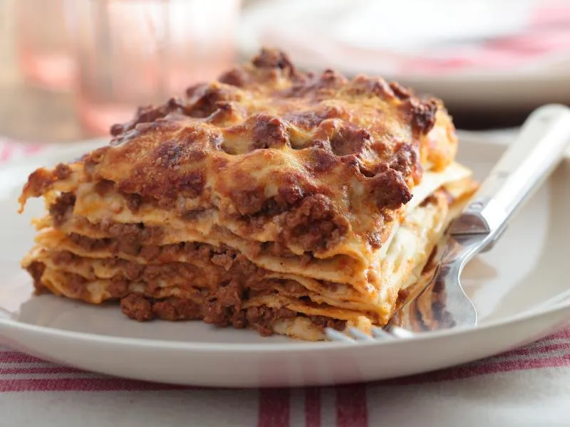 A baked square of lasagna with meat sauce and a browned cheese surface
