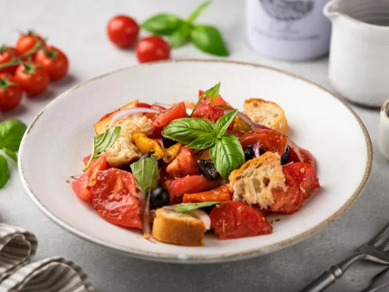 Tomato and bread salad with basil and red onion in a white bowl
