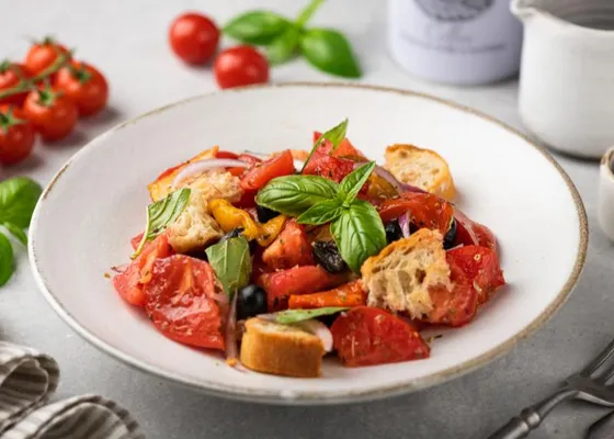 Tomato and bread salad with basil and red onion in a white bowl