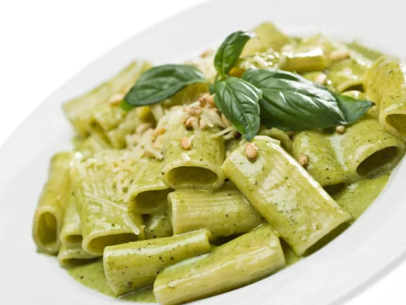 Ridged short pasta coated in green basil pesto, topped with basil leaves, pine nuts and grated cheese
