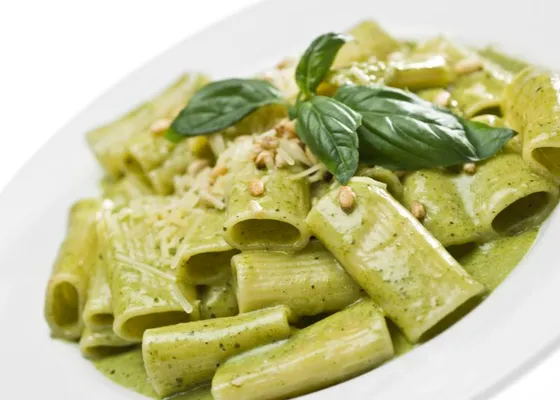 Ridged short pasta coated in green basil pesto, topped with basil leaves, pine nuts and grated cheese