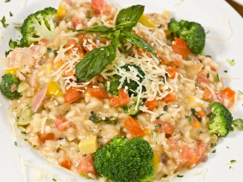 Risotto with broccoli florets, diced tomato, zucchini and red onion, topped with grated cheese and basil