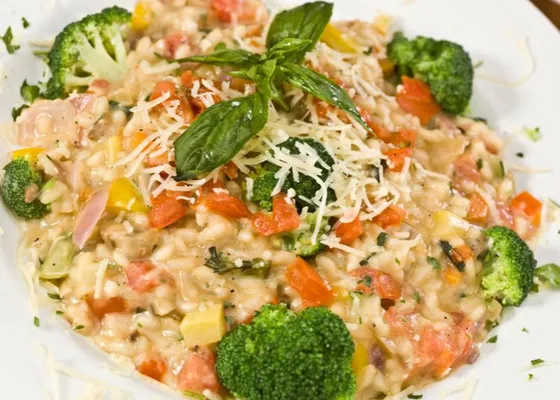 Risotto with broccoli florets, diced tomato, zucchini and red onion, topped with grated cheese and basil