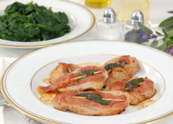 Flat veal cutlets topped with prosciutto and sage, with greens served separately