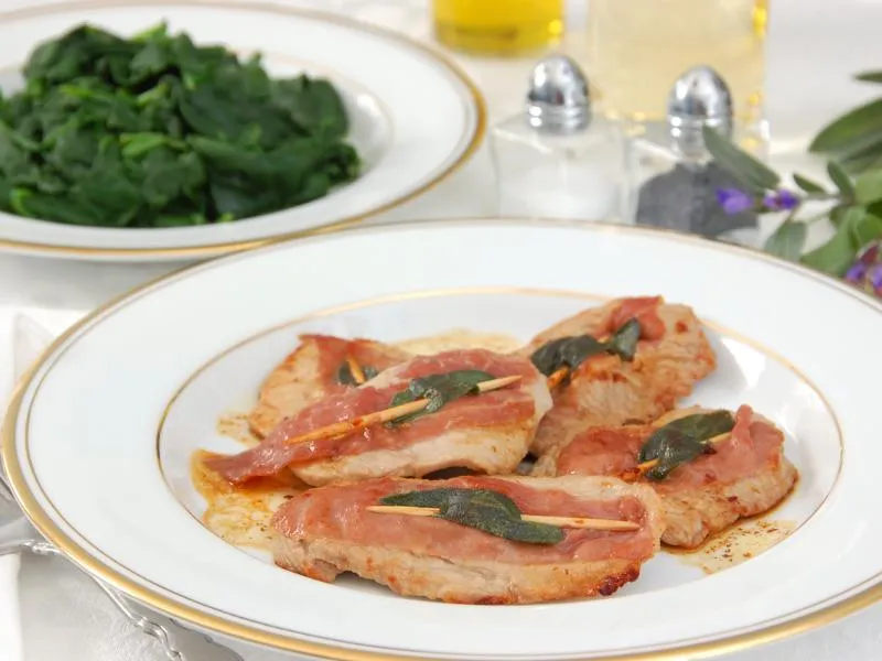 Flat veal cutlets topped with prosciutto and sage, with greens served separately