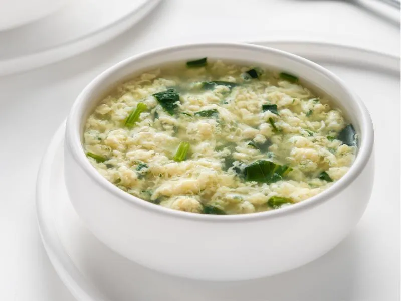 Egg ribbons in a bowl of broth with leafy greens