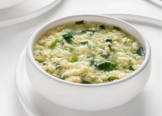 Egg ribbons in a bowl of broth with leafy greens