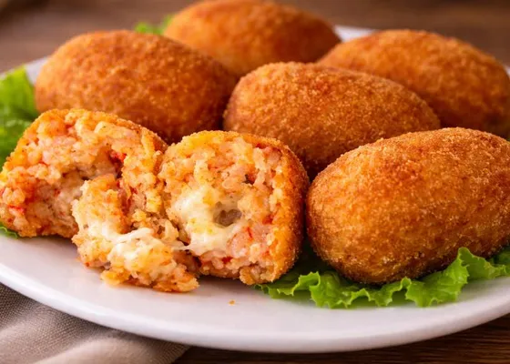 Golden oblong rice croquettes, one cut open to show tomato rice and mozzarella